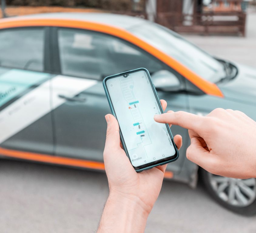 11 May 2020, Ufa, Russia: young person on a smartphone books a car in the Delimobil carsharing app to get around the city. New generation chooses not to own a car but to rent a vehicle