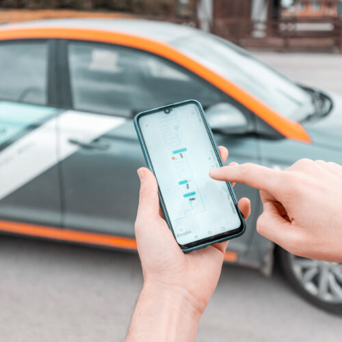 11 May 2020, Ufa, Russia: young person on a smartphone books a car in the Delimobil carsharing app to get around the city. New generation chooses not to own a car but to rent a vehicle